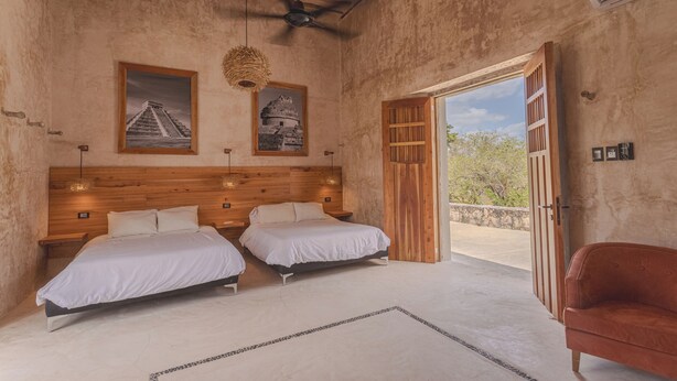 A bedroom with two beds, a ceiling fan, and a large window. - Hacienda San José Xuilub (Espita)