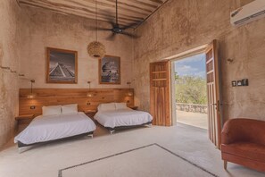 Een slaapkamer met twee bedden, een plafondventilator en een groot raam.