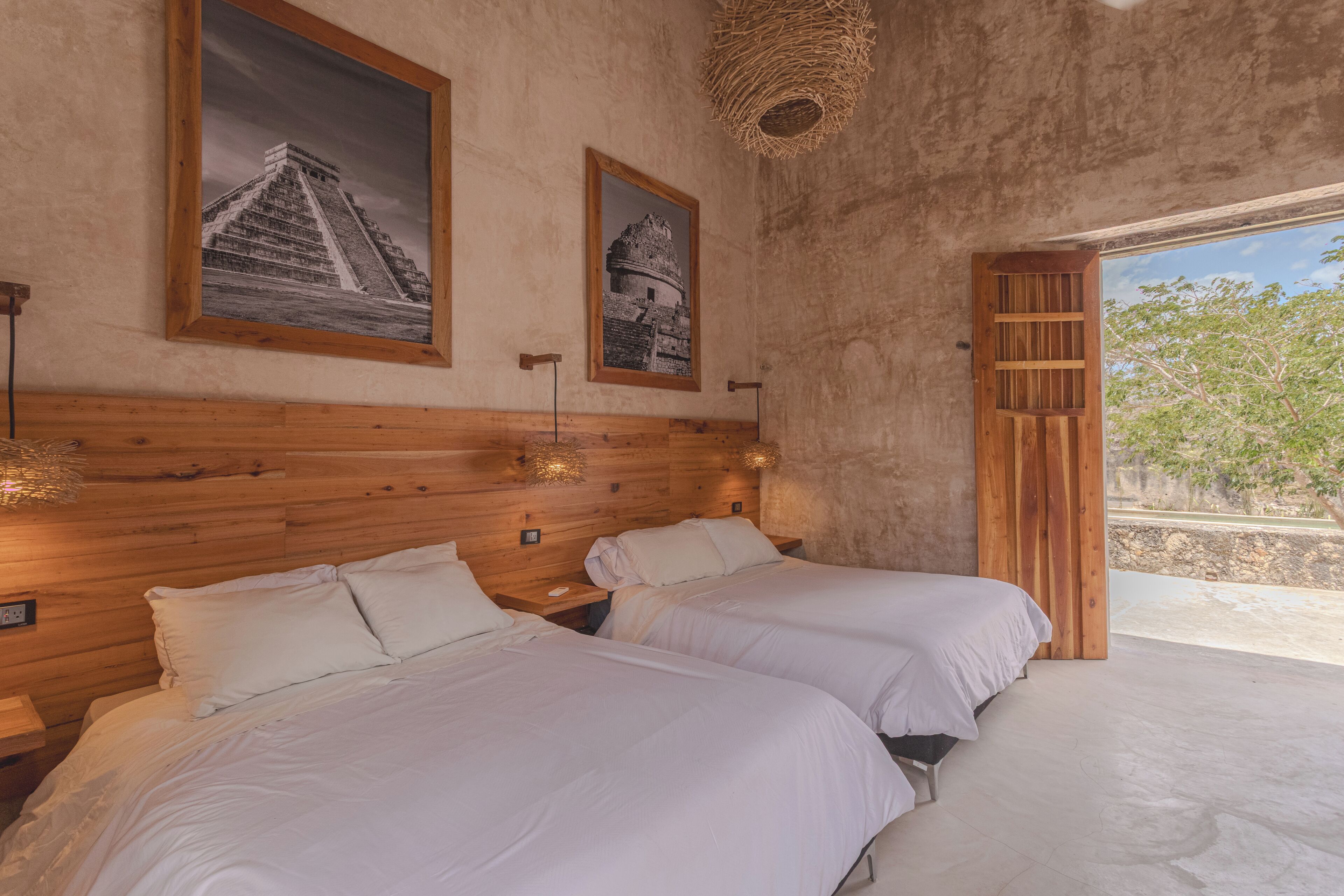 A room with two beds, wooden headboard, and two framed pictures on the wall.