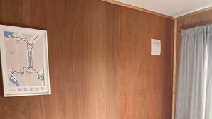 Una habitación con una pared de madera, un sofá verde, una pequeña mesa con una caja de pañuelos y un mapa en la pared.