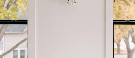 Un comedor con una mesa blanca, sillas coloridas y un adorno en la pared.
