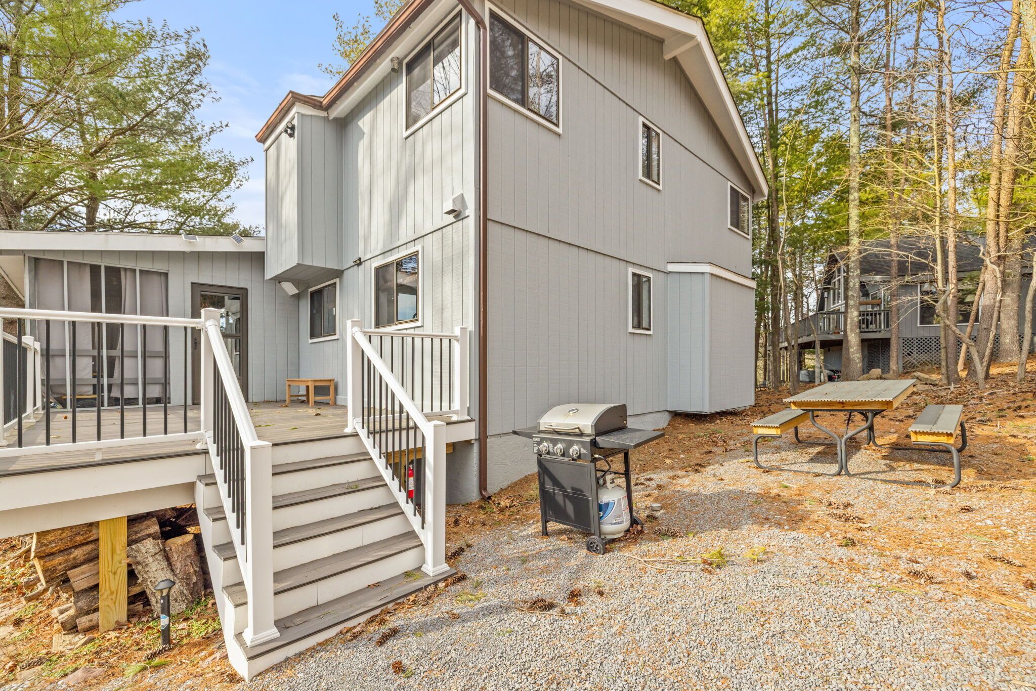 A two-story building with a covered porch, a grill, and a picnic table.