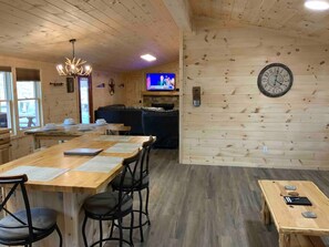 A wooden interior with a long dining table, chairs, a television, and a clock on the wall. - Close to Dollywood quiet area fenced yard for dogs (Sevierville)