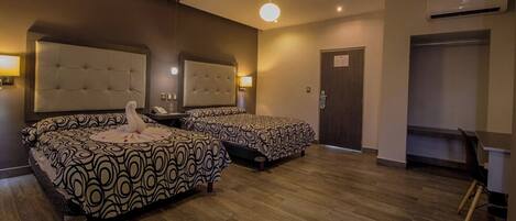 A hotel room with two beds, a sitting area, a desk, and a wardrobe.