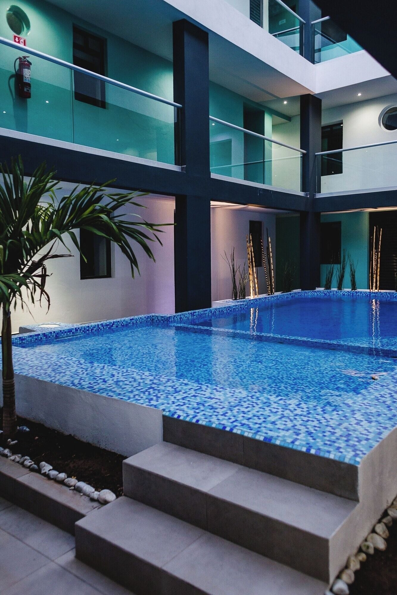 Un bâtiment moderne doté d’une piscine, de rampes en verre et d’un extincteur.