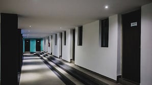 Un passadís llarg i estret amb una sèrie de portes a un costat i una escala a l'altre.