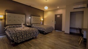 Une chambre d’hôtel avec deux lits, un coin salon, un bureau et une armoire.
