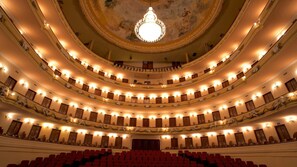 Un teatro a più livelli con balconi decorati e un lampadario centrale.