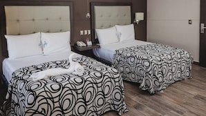 Two beds with patterned bedspreads, a bedside table with a lamp, and a rolled towel on the floor. - Experience a Convenient, Relaxing, and Comfortable Stay in Downtown Merida (Mérida)