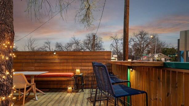 Un patio in legno con tavolo e sedie, una panca e luci a tenda.