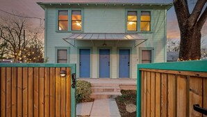 Una casa a due piani con un portico, una strada privata e un recinto in legno.