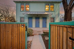 A two-story house with a front porch, a driveway, and a wooden fence. - Ted & Breakfast | Chic East Austin Retreat (Austin)