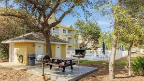 Un bâtiment jaune doté d’un patio couvert, d’un barbecue et d’une table de pique-nique.