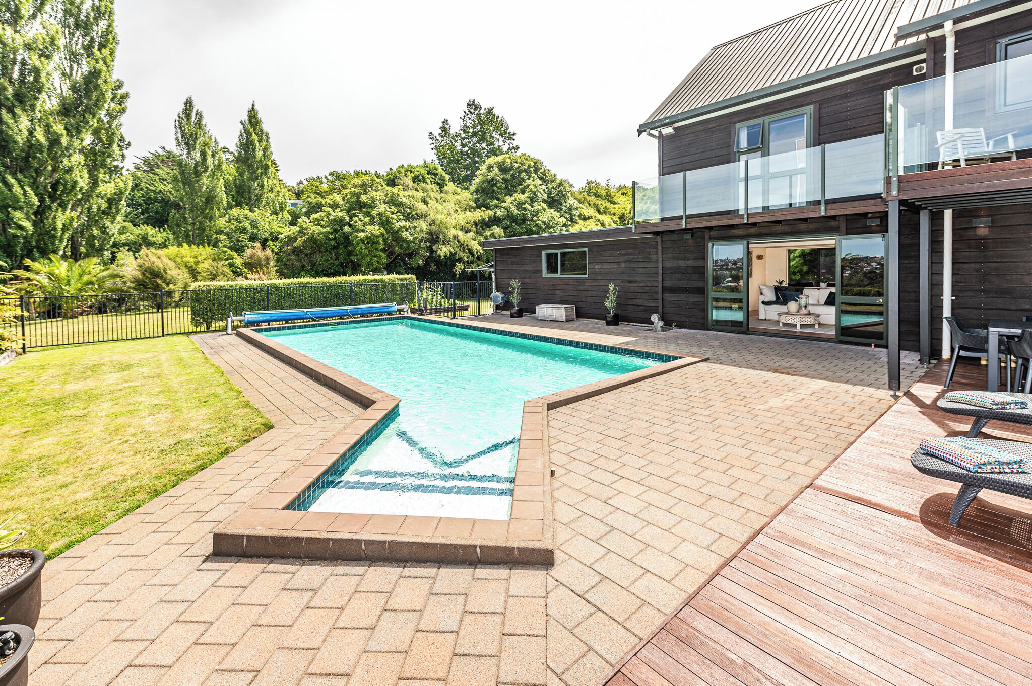 A modern house with a swimming pool, outdoor seating, and a well-maintained garden.