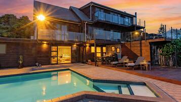 A modern two-story house with a swimming pool, outdoor seating, and a balcony.