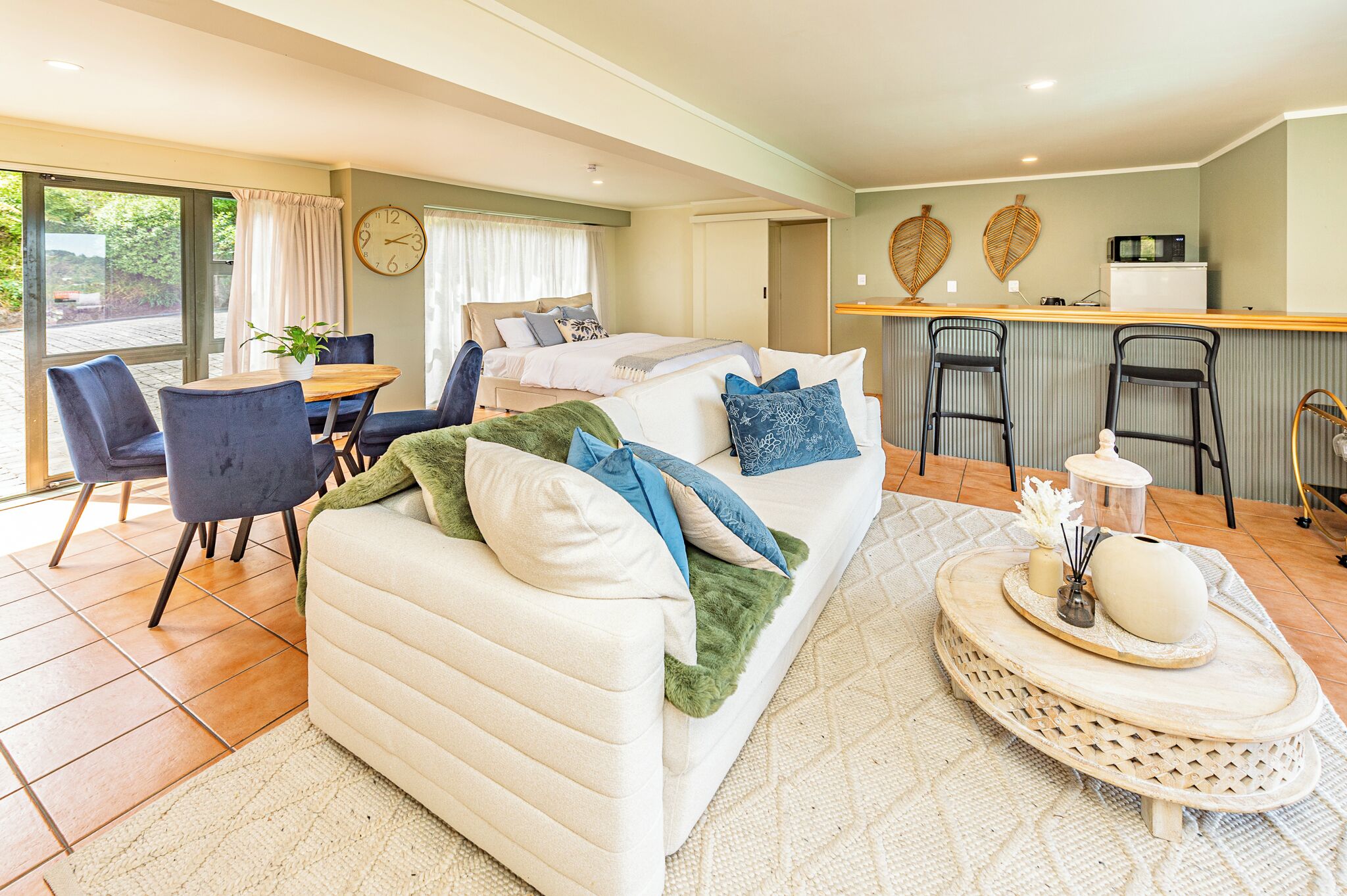 A modern living room with a sofa, a dining table, and a kitchen area with a bar counter.