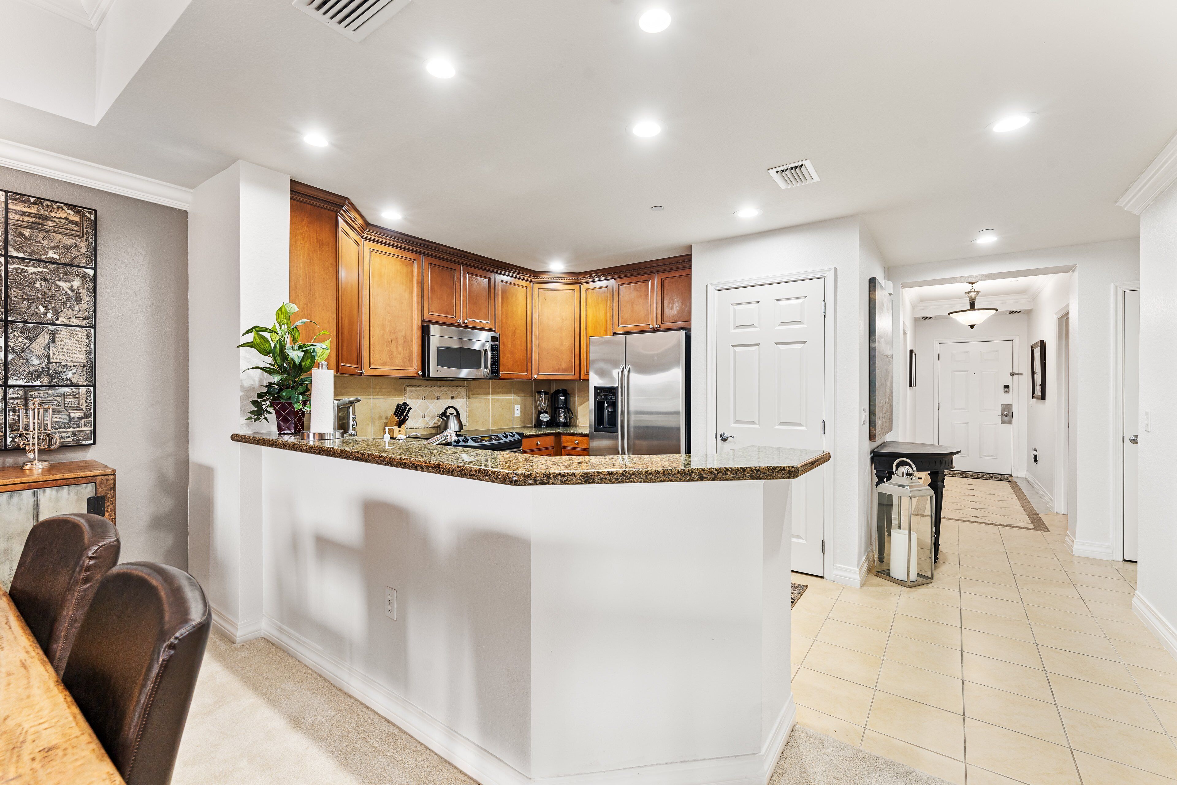 A modern kitchen with wooden cabinets, stainless steel appliances, and a granite countertop.