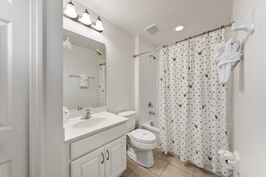Een badkamer met een wit wastafel, toilet en douchegordijn met stippen.