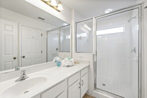 Een moderne badkamer met een grote spiegel, een wastafel en een inloopdouche.