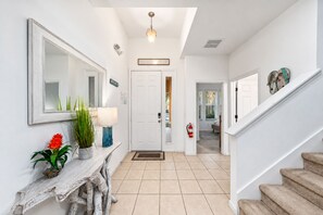 A hallway with a white door, a mirror, a lamp, and a plant. - Home with Screened Private Pool and Preserve Views (Davenport)