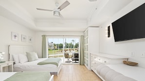 A bedroom with a bed, a desk, a chair, a TV, and a balcony with a view. - Beautiful Townhouse with Golf Course Views, Near Attractions (Kissimmee)