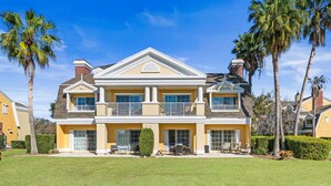 A two-story house with a balcony, large windows, and a well-maintained lawn. - Beautiful Townhouse with Golf Course Views, Near Attractions (Kissimmee)