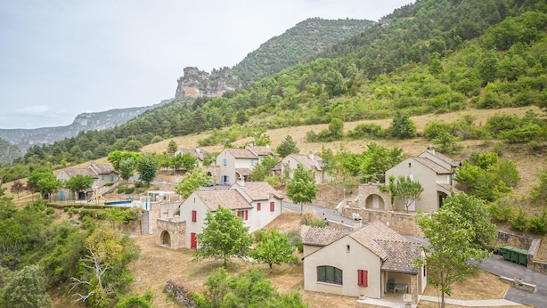 Un borgo collinare con case tradizionali, strette vie e un'imponente scogliera sullo sfondo.
