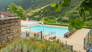 Piscina con muro in pietra e vista su un paesaggio montano.