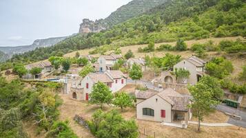 Un pueblo en la ladera de una colina con casas tradicionales, calles estrechas y un imponente risco al fondo.