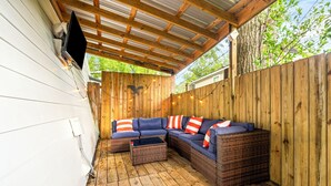 A covered outdoor seating area with a wooden floor, a sectional sofa with cushions, and a small table. - Chic Downtown Auburn Townhome! 2/1.5 (Auburn)