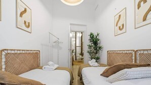 A hotel room with two single beds, a mirror, a hanging plant, and framed artwork on the walls. - Classic Malasaña (Madrid)