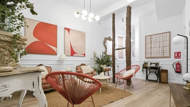 A spacious living room with a large window, a fireplace, and a dining area with red chairs. - Classic Malasaña (Madrid)