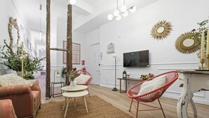 A modern living room with a sofa, two red chairs, a coffee table, and a TV on the wall. - Classic Malasaña (Madrid)