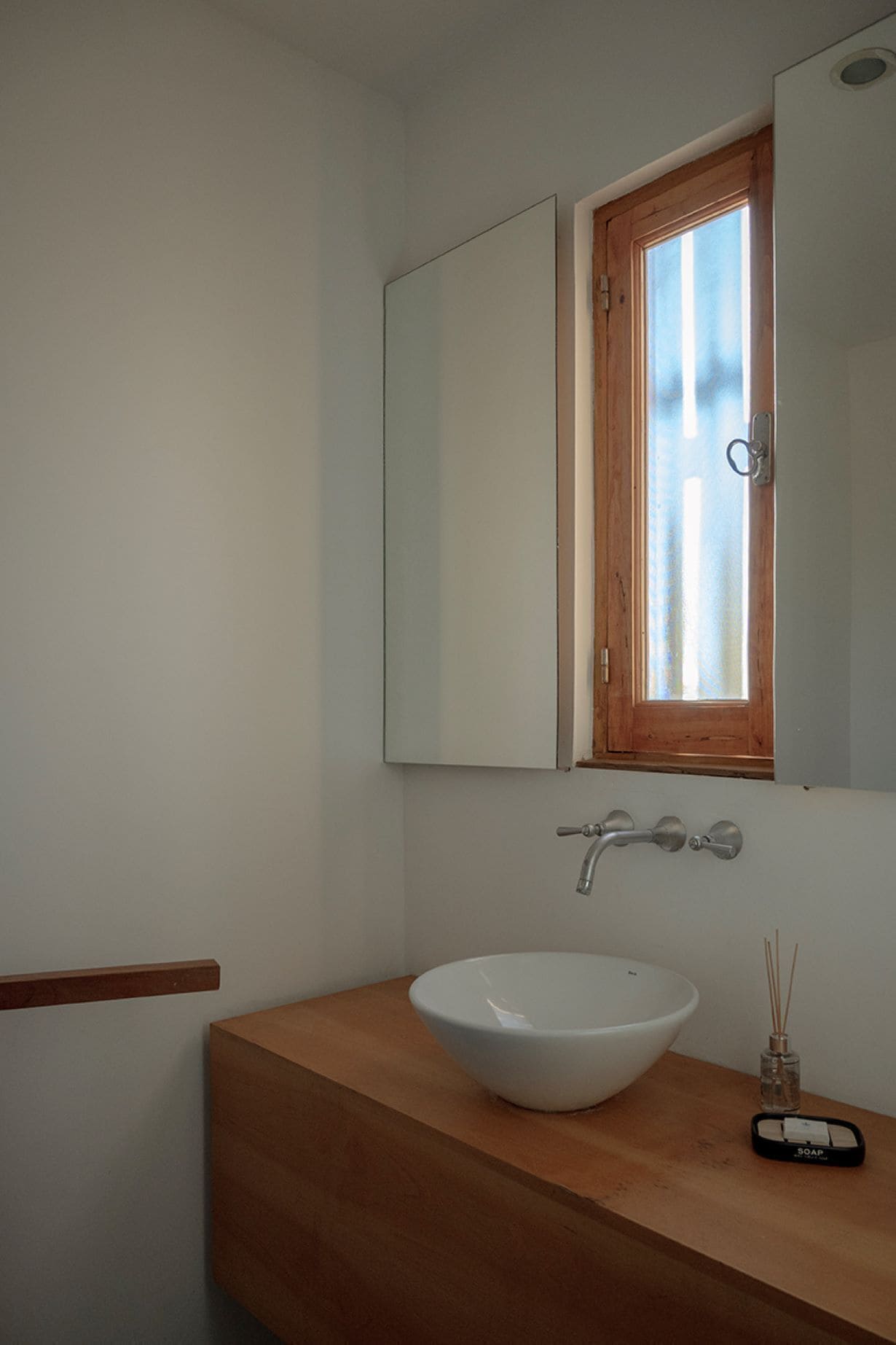A bathroom with a white sink, wooden countertop, and a mirror above it.