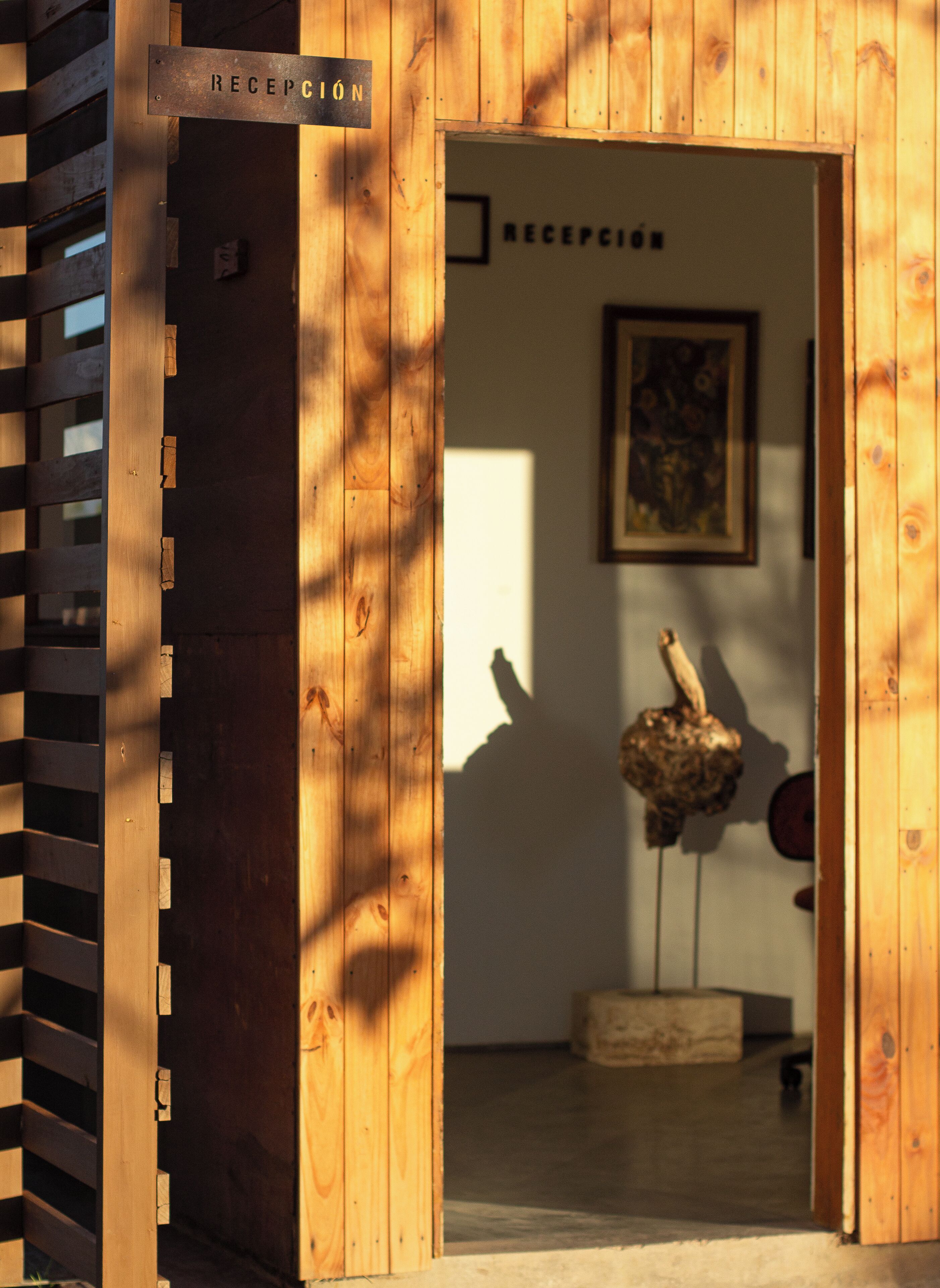 Un área de recepción de madera con un cartel, una obra de arte enmarcada y una escultura.