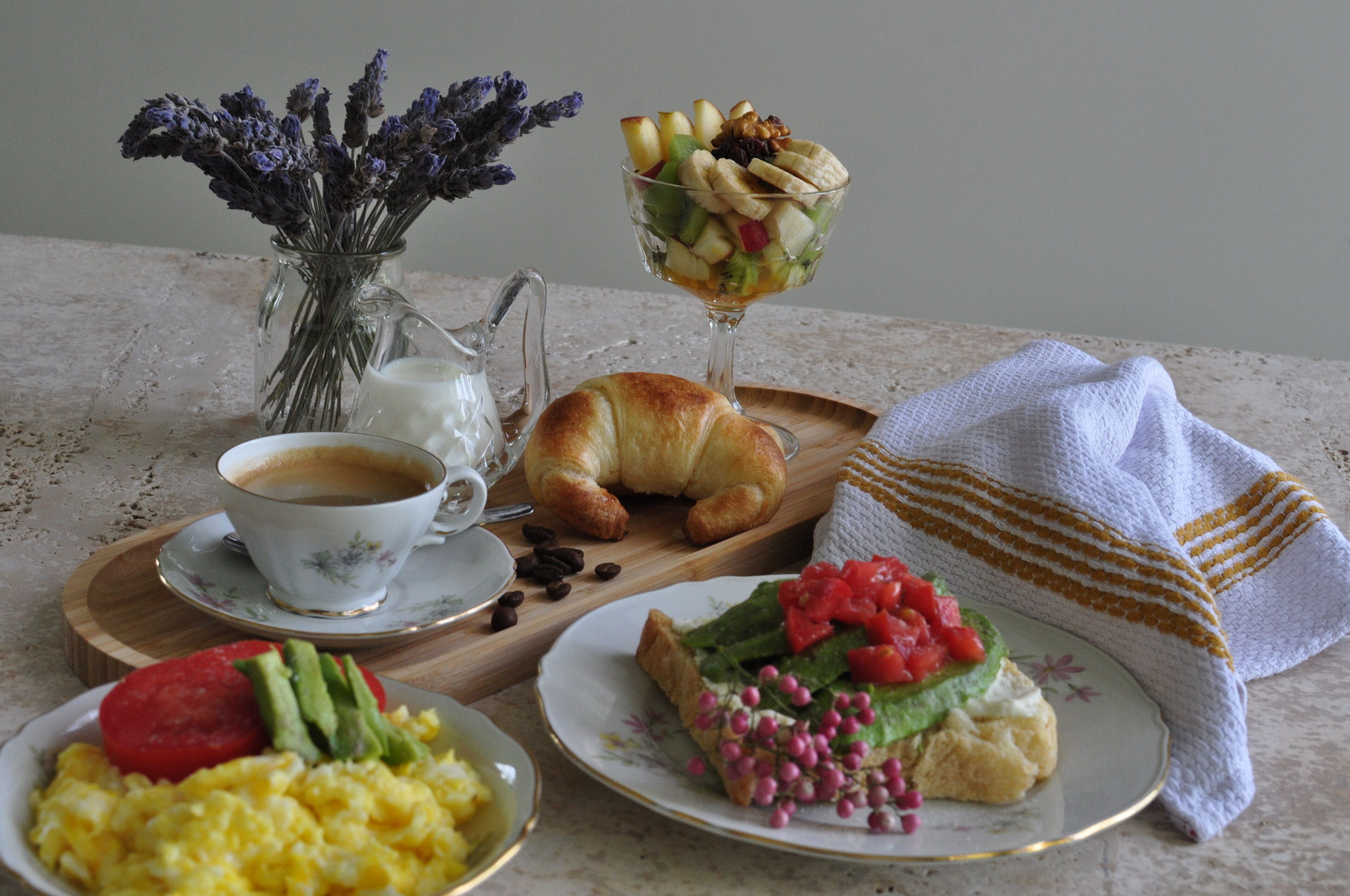 Een ontbijt met croissants, fruitsalade, roerei en koffie.