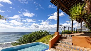 En swimmingpool med utsikt över havet, en trappa med mönstrade plattor och en palmplanta.