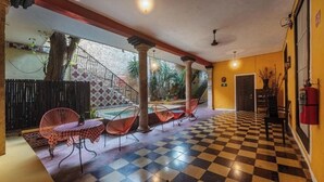 A hotel lobby with checkered flooring, red chairs, a staircase, and a view of the outside. - Comfortable Room Perfect for Exploring Mérida’s Historic Sights & Culture (Mérida)