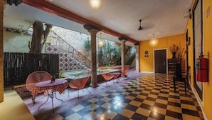 A hotel lobby with checkered flooring, red chairs, a staircase, and a view of the outside. - Spacious 3 Room Units Perfect for City Adventures and Group Getaways (Mérida)