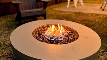 A circular outdoor fire pit with a metal rim and a central fire.