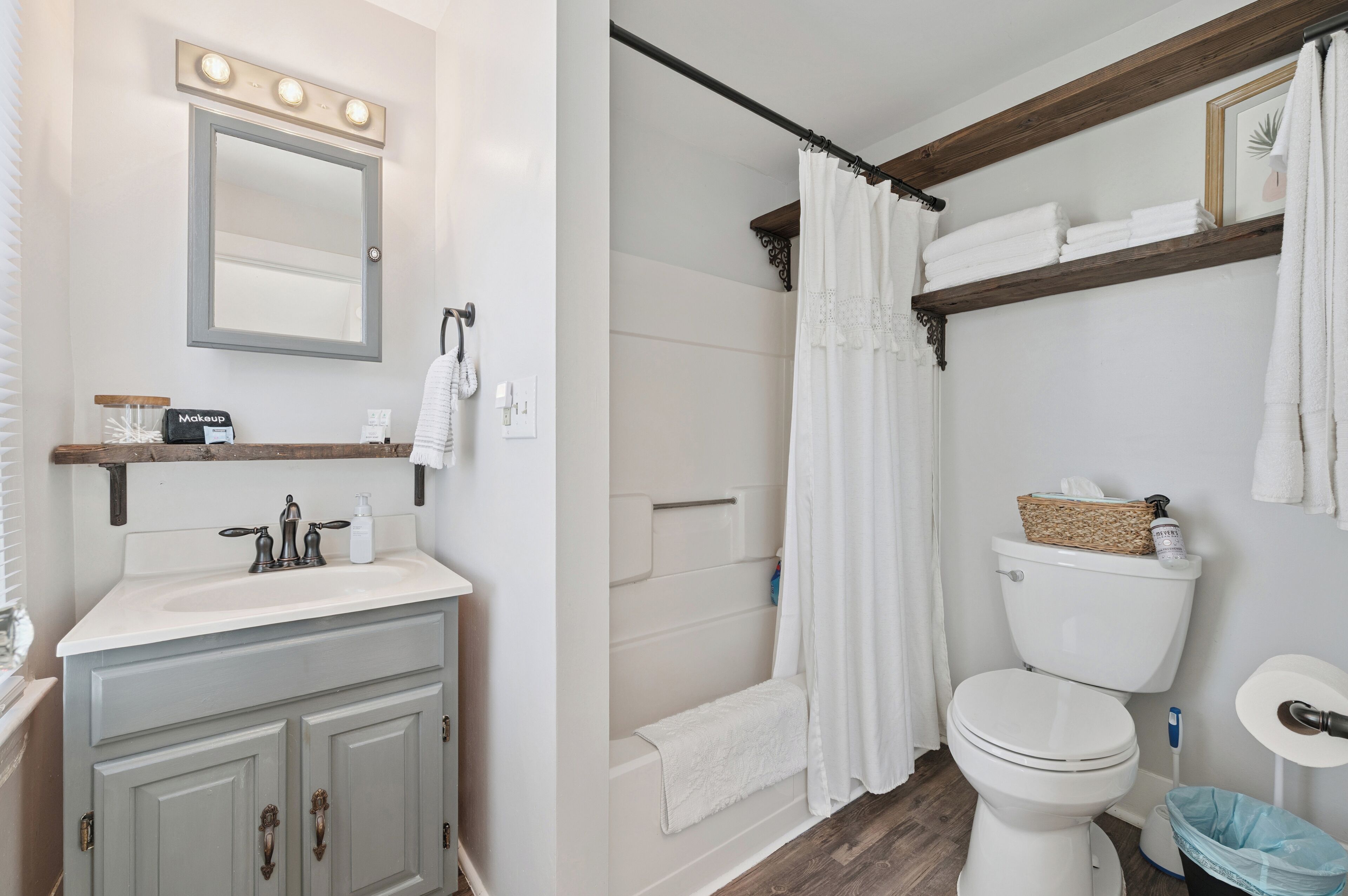 Een badkamer met een wastafel, spiegel, douche, toilet en handdoekrek.