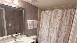 Ein Badezimmer mit großem Spiegel, Waschbecken, Toilette und Duschvorhang.