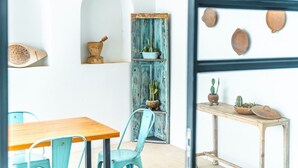 A dining area with a wooden table and turquoise chairs, a rustic blue cabinet with plants, and a wall with decorative pottery. - Villa deluxe with private pool in the most quiet area of Tamarindo up to 4 ppl (Tamarindo)