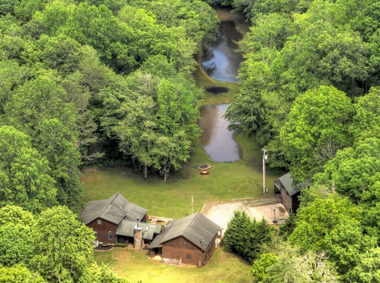 A cabin surrounded by dense forest with a small stream running through it.