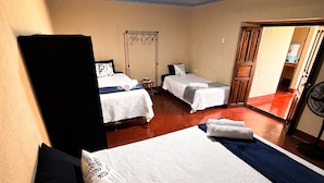 A hotel room with two beds, a wardrobe, a small table, and a fan. - Casa Luna | Best Location | Walk Everywhere (Antigua Guatemala)