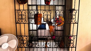A room with a barred window, a fan, and decorative items including masks and a small potted plant. - Casa Luna | Best Location | Walk Everywhere (Antigua Guatemala)