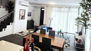 Eine moderne Küche mit Essbereich, einer Treppe und einem Wohnzimmer mit großem Fenster.