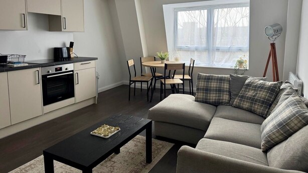Un salon moderne comprenant un canapé, une table à manger et un coin cuisine avec des placards et des appareils électroménagers.