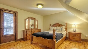 Un dormitorio con una cama de madera, un aparador, una mesita de noche, un espejo y una puerta con persianas.