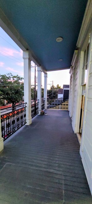 Ein überdachter Außenbereich mit Balkon, Säulen und Geländer.